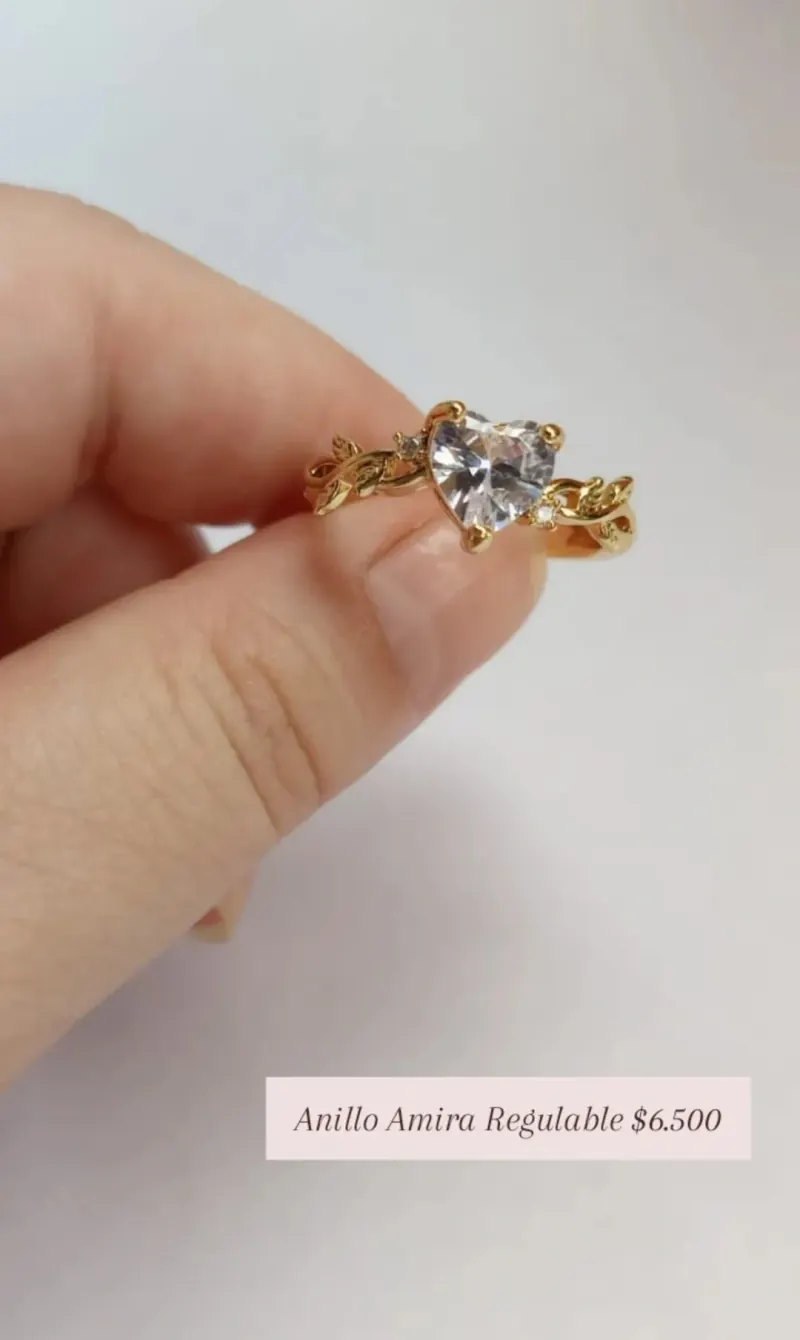Anillo Amira Regulable: anillo dorado con corazón de cristal transparente y banda calada.