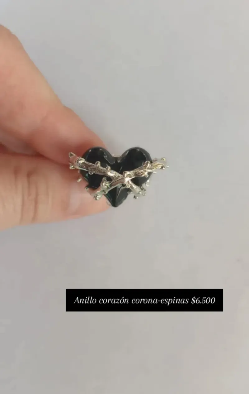 Anillo corazón corona-espinas: corazón negro rodeado por una rama de espinas plateada.
